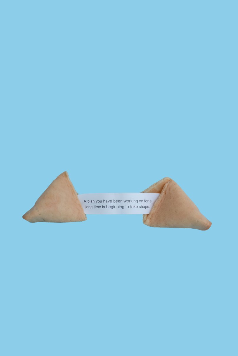 An image of a split fortune cookie with a fortune that reads, 